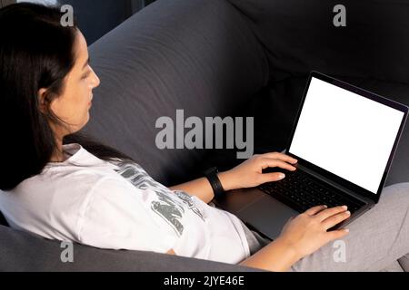 Laptop-Modell, Porträt einer Frau, die einen Laptop-Modell hält. Blick von der Seite nach oben auf den weißen weißen, weißen Bildschirm eines modernen Notizbuchs mit kaukasischer Frau in einem dunklen Zimmer. Stockfoto
