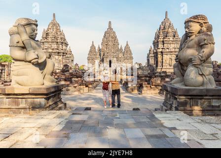 Ein junges Paar, das mit offenen Armen steht und den Sewu-Tempel anschaut. Sewu ist nach dem Borobudur-Tempel in Indonesien der größte buddhistische Tempel. Dies ist lokat Stockfoto