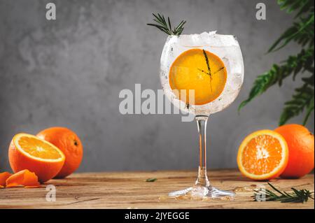 Gin Tonic Orangencocktail, Longdrink mit trockenem Gin, Bitter Tonic, Rosmarin und Eis. Holztisch Hintergrund mit Kopieplatz Stockfoto