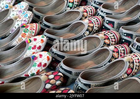 Bunte handgemachte Chappalls (Sandalen), die auf einem indischen Markt verkauft werden, handgefertigte Lederschuhe, traditionelle Schuhe. Stockfoto