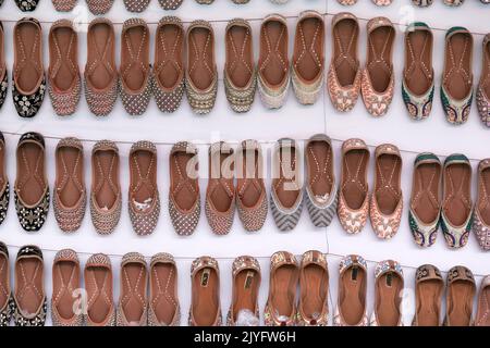 Bunte handgemachte Chappalls (Sandalen), die auf einem indischen Markt verkauft werden, handgefertigte Lederschuhe, traditionelle Schuhe. Stockfoto