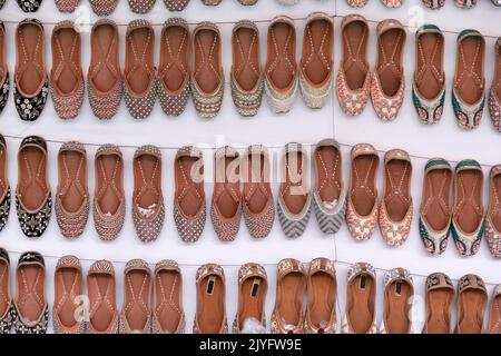 Bunte handgemachte Chappalls (Sandalen), die auf einem indischen Markt verkauft werden, handgefertigte Lederschuhe, traditionelle Schuhe. Stockfoto