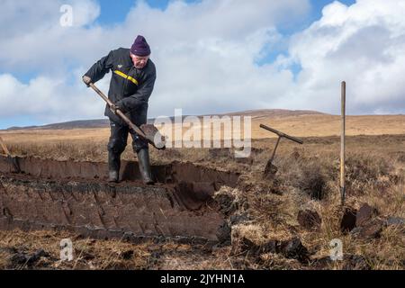 Ein Rasenmäher mitten im ausgedehnten Torfmoor am Rande des Wild Nephin National Park. Er schneidet seinen Rasen von Hand, mit einem Sléan. Stockfoto