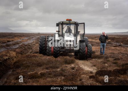 Rasenschnitt mit einer Sausager-Maschine hinter einem Traktor. An ruft mit einem Kunden an. Stockfoto