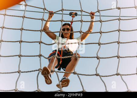 Junge Kletterer, die Schwierigkeiten haben, im Abenteuerpark an der Seile zu hängen Stockfoto