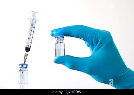 Hand in Handschuhe halten ein Glas mit Impfstoff, Injektion, ausgeschnitten Stockfoto