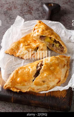 Frisch gebackene hausgemachte Cornish Pasties auf dem Papier auf dem Holzbrett. Vertikal Stockfoto