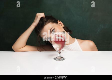 Moderne Kunstfotografie. Komisches, seltsames Mädchengesicht durch ein Glas Wasser. Objektverzerrung, optische Täuschung. Minimalistische zeitgenössische Kunst Stockfoto