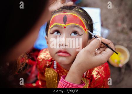 Kathmandu, Nepal. 16. September 2022. Eine Künstlerin bereitet ein junges Mädchen auf den Kumari Puja auf dem Hanumandhoka Durbar Platz vor. Das jährliche Festival, benannt nach Indra, dem gott des Regens und Himmels, wird im Kathmandu Valley zum Abschluss der Monsunsaison durch Anbeten, Jubeln, Singen, Tanzen und Schlemmen gefeiert. Indra, die lebende Göttin Kumari und andere Gottheiten werden während des Festes verehrt. Kredit: SOPA Images Limited/Alamy Live Nachrichten Stockfoto