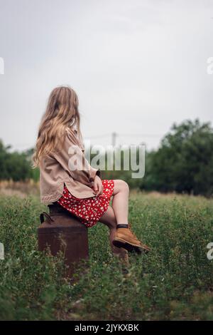 Ländliche Ästhetik. Mädchen sitzt auf einer alten Milchkänne Stockfoto