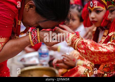 Eine Frau betet an die Hand eines Kindes, das als lebende Göttin Kumari gekleidet ist, als Teil eines religiösen Rituals während der Kumari Puja Prozession, die anlässlich des Indra Jatra Festivals in Kathmandu organisiert wurde. Das jährliche Festival, benannt nach Indra, dem gott des Regens und Himmels, wird im Kathmandu Valley zum Abschluss der Monsunsaison durch Anbeten, Jubeln, Singen, Tanzen und Schlemmen gefeiert. Indra, die lebende Göttin Kumari und andere Gottheiten werden während des Festes verehrt. (Foto von Prabin Ranabhat/SOPA Images/Sipa USA) Stockfoto