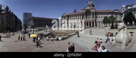 Eine Panoramaansicht des Victoria Square Birmingham. Zum Rathaus (Mitte) führen Stufen, die von zwei Sphynx-Skulpturen aus Dove Dale-Stein mit der Dhruva Mistry-FLUSSSTATUE umrahmt werden, die lokal als die Floozie im Whirlpool oben bezeichnet wird. Rechts befindet sich das Rathaus mit Säulen und der Skyline des Alpha Towers. Stockfoto