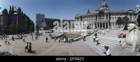 Eine Panoramaansicht des Victoria Square Birmingham. Zum Rathaus (Mitte) führen Stufen, die von zwei Sphynx-Skulpturen aus Dove Dale-Stein mit der Dhruva Mistry-FLUSSSTATUE umrahmt werden, die lokal als die Floozie im Whirlpool oben bezeichnet wird. Rechts befindet sich das Rathaus mit Säulen und der Skyline des Alpha Towers. Stockfoto