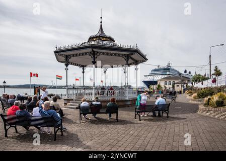 Der Bandstand im John F. Kennedy Memorial Park in Cobh, Südwestirland, mit dem Kreuzschiff „Celebrity Silhouette“ im Hafen für den Tag. Stockfoto