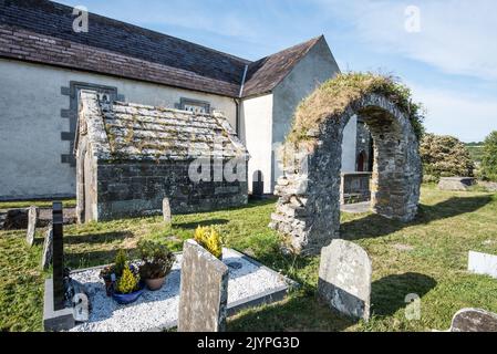 Reste eines alten Bogens sowie eines kleinen Steingebäudes auf dem Kirchhof neben der St. Fachtna-Kathedrale in Rosscarbery, Cork, S. W. Irland. Stockfoto