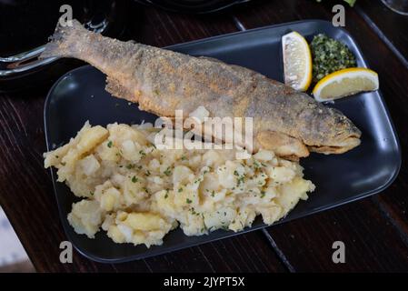 Gebratener Forellenfisch, serviert mit Kartoffelpüree und einem kleinen frischen Salat Stockfoto