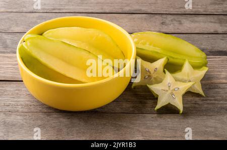 Starfruits mit Scheiben in einer Schüssel über einem Holztisch. Stockfoto