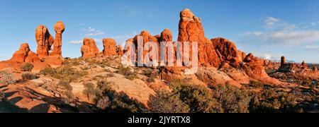 Der Mond steigt über den Sandsteinfelsen des Garden of Eden im Arches National Park, Moab, Utah. Beachten Sie Felskletterer auf Owl Rock in der Mitte rechts. Stockfoto