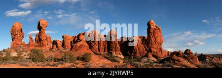 Der Mond steigt über den Sandsteinfelsen des Garden of Eden im Arches National Park, Moab, Utah. Beachten Sie Felskletterer auf Owl Rock auf der rechten Seite. Stockfoto