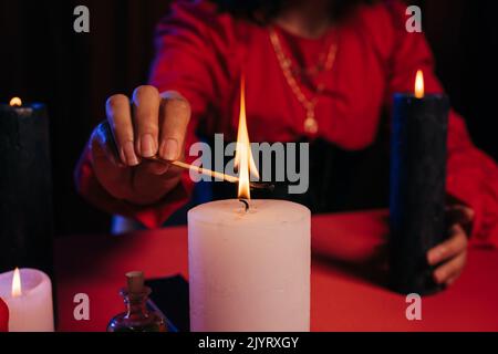 Beschnittene Ansicht der verschwommenen Wahrsagerin Beleuchtung palo santo Stick in der Nähe brennende Kerze isoliert auf schwarz Stockfoto