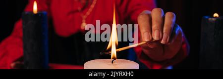 Teilansicht der Wahrsagerbeleuchtung palo santo Stick in der Nähe brennende Kerze isoliert auf schwarzem Banner Stockfoto