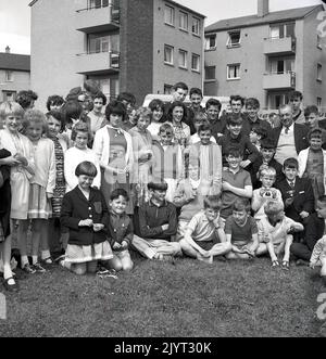 1965, historisch, draußen auf einem öffentlichen Wohngebiet, versammelten sich Jugendliche zu einem Gruppenbild, einige mit Miniaturtrophäen, nachdem sie an der North Queensferry Gala, Fife, Schottland, Großbritannien, teilgenommen hatten. Stockfoto