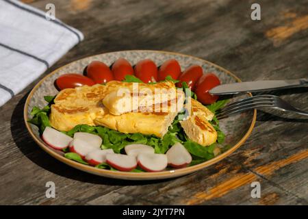 Europäisches Frühstück. Ein leichtes Frühstück mit französischem Omelett mit Radieschen, Spinattomaten und Rucola. Stockfoto