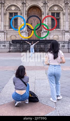 Asiatische Touristen fotografieren vor dem Schild der Olpymic Games am Hôtel de Ville, dem Rathaus von Paris, Frankreich Stockfoto