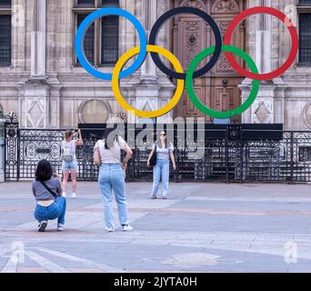 Asiatische Touristen fotografieren vor dem Schild der Olpymic Games am Hôtel de Ville, dem Rathaus von Paris, Frankreich Stockfoto