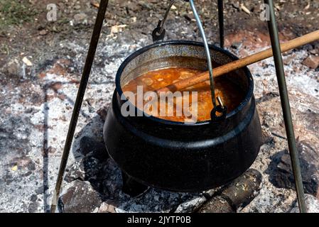 Kochen von Gulasch in einem Kessel auf einem offenen Feuer in der Natur. Stockfoto