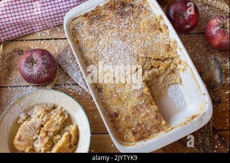 Süßer Auflauf zum Frühstück. Gekocht mit Hirse, Äpfeln, Eiern und Quark. Serviert in einer Auflaufform auf rustikalem und Holztisch Hintergrund Stockfoto