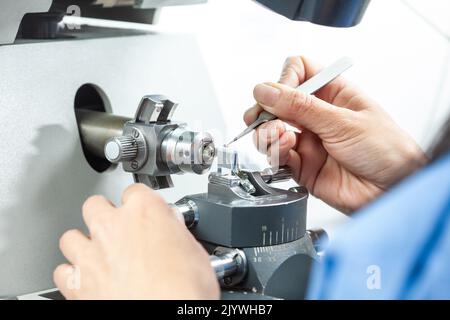 Nahaufnahme einer Wissenschaftlerin, die eine Probe auf ein Transmissions-Elektronenmikroskopieraster platziert Stockfoto