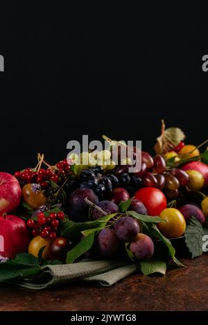 Stillleben von Herbstfrüchten und Beeren auf dunklem Grund Stockfoto