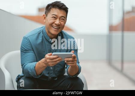 Lächelnder asiatischer Geschäftsmann, der in der Pausenzeit telefoniert Stockfoto