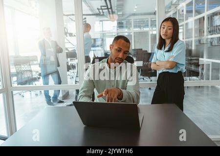 Zwei multiethnische Kollegen aus der Wirtschaft arbeiten in einem modernen Büro zusammen Stockfoto
