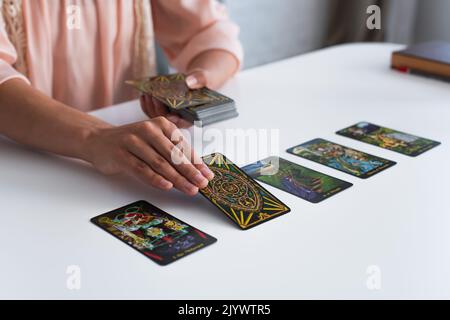 KIEW, UKRAINE - 29. JUNI 2022: Teilansicht des Wahrsagerin, der Tarot-Karten auf den Tisch legt Stockfoto