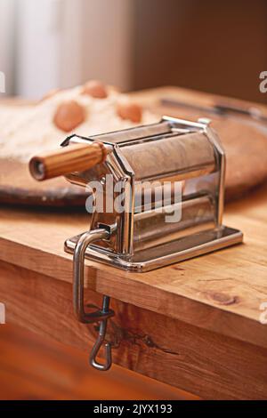 Verwenden Sie diese, um Ihre Pasta schneller zu Rollen. Eine Pastamaschine auf einem Tisch in einer Küche. Stockfoto