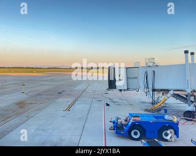 Internationaler Flughafen GSP mit einer Jet-Brücke und einem Rückzugschlepper, der während des Morgensonnenaufgangs auf dem Asphalt sitzt. Stockfoto