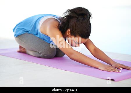 Erreichen ihrer Fitnessziele. Eine junge Frau, die draußen Yoga macht. Stockfoto