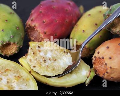 Nahaufnahme einer halbierten Kaktusfeige mit Kaktusfeige, opuntia-Frucht mit Löffel auf schwarzem Hintergrund Stockfoto