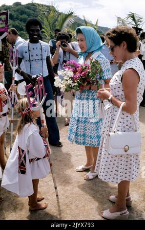 Aktenfoto vom 30/10/1977 von Königin Elizabeth II. (Zweite links), begleitet von Prinzessin Margaret, die von einer jungen Insel in schickem Kleid auf der Insel Mustique ein schickes Foto erhielt. Wie Buckingham Palace mitteilte, starb die Königin heute Nachmittag friedlich in Balmoral. Ausgabedatum: Donnerstag, 8. September 2022. Stockfoto