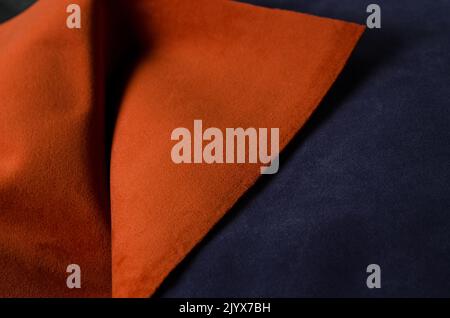 In den Farben Orange und Dunkelblau sind weiche Veloursstoffe erhältlich. Hintergrund mit Stofftextur. Stockfoto