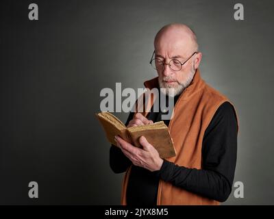 Kopf- und Schulterporträt eines kahlen und bärtigen älteren Mannes, der ein Tagebuch schreibt Stockfoto