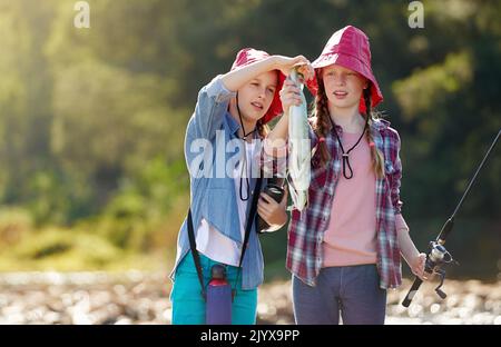 Bewundern ihren Fang. Zwei junge Mädchen fischen an einem Fluss. Stockfoto