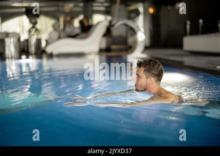 Mann, der im Pool im Spa Resort schwimmt Stockfoto