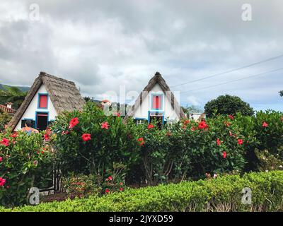 Traditionelle alte Häuser mit Strohdächern im Dorf und einem schönen Garten. Santana, Madeira. Stockfoto