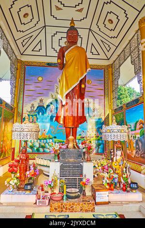 PAI, THAILAND - 6. MAI 2019: Innenansicht des Schreins des Wat Pa Kham Tempels mit einer Statue des stehenden Buddha mit bemalten Wänden und Decke um ihn herum, o Stockfoto