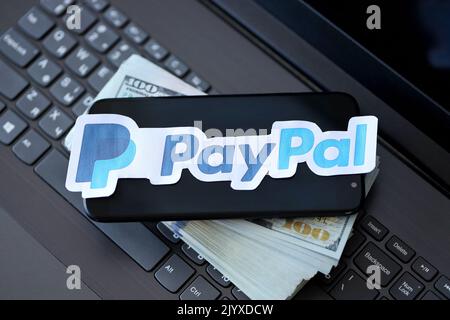 TERNOPIL, UKRAINE - 6. SEPTEMBER 2022 das Paypal-Papierlogo liegt auf einer schwarzen Laptop-Tastatur mit US-Dollar-Scheinen. Payoneer ist ein amerikanischer Finanzdienstleister Stockfoto