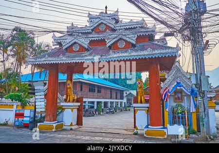 Das Tor zum Wat Pa Kham Tempel mit einem Gewirr von elektrischen Drähten auf dem Pol daneben, Pai, Thailand Stockfoto