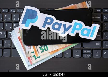 TERNOPIL, UKRAINE - 6. SEPTEMBER 2022 Paypal-Papier-Logo liegt auf schwarzer Laptop-Tastatur mit Euro-Rechnungen. Payoneer ist American Financial Services com Stockfoto